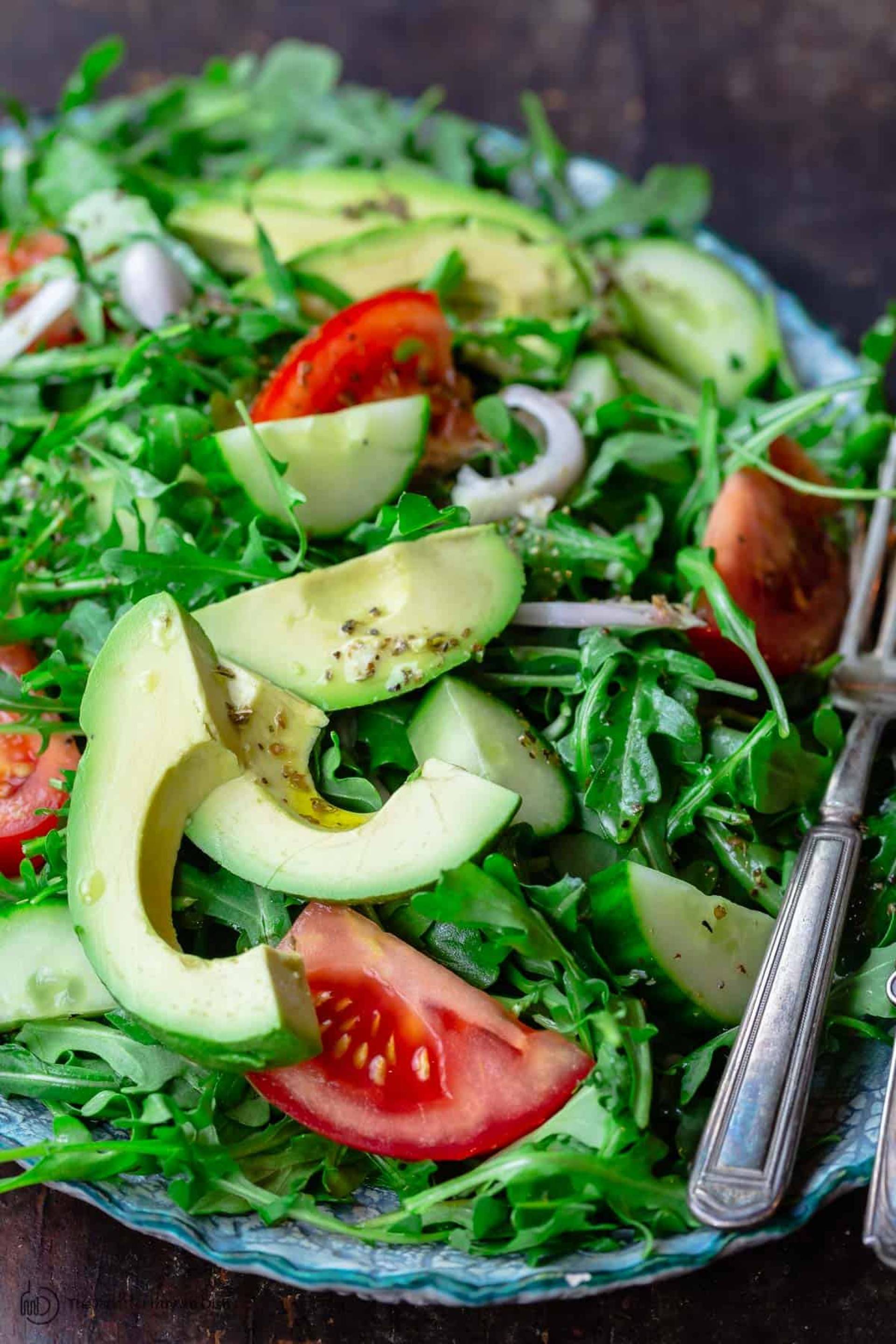 Biftec de pollo encebollado con ensalada de arugula, tomate y aguacate