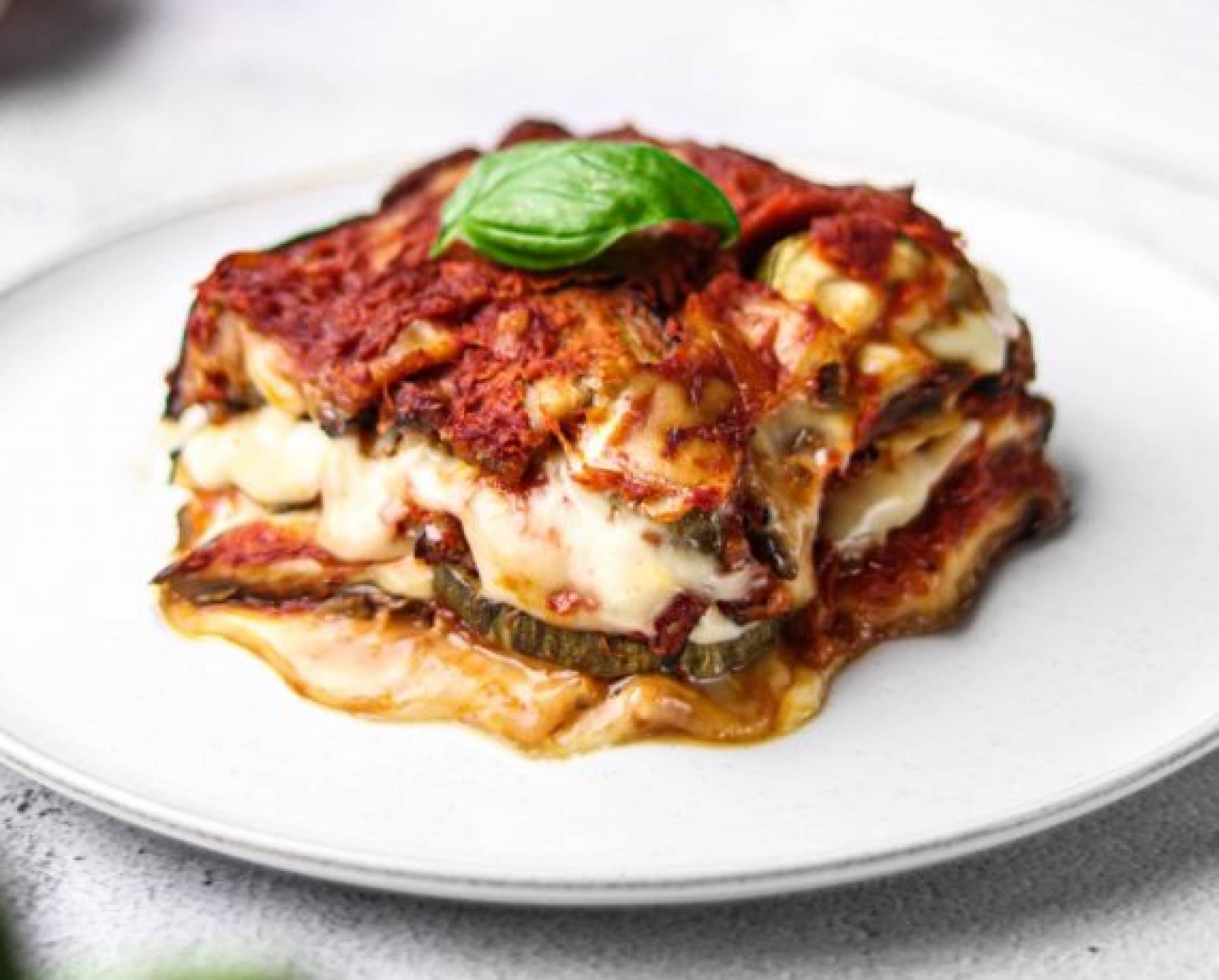 Lasagna de berenjena de pollo servida con ensalada verde