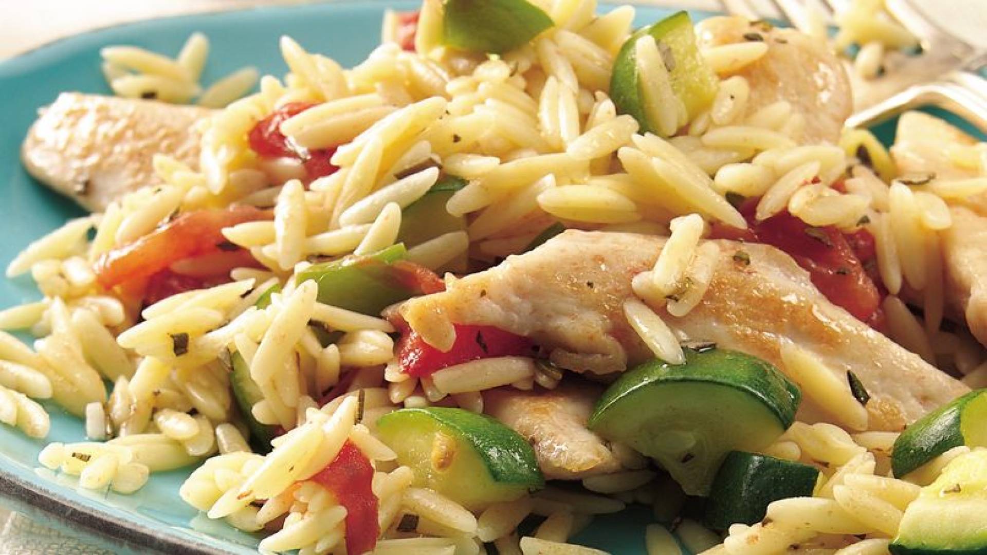 Pechuga de pollo a la parrilla servida con pasta orzo primavera